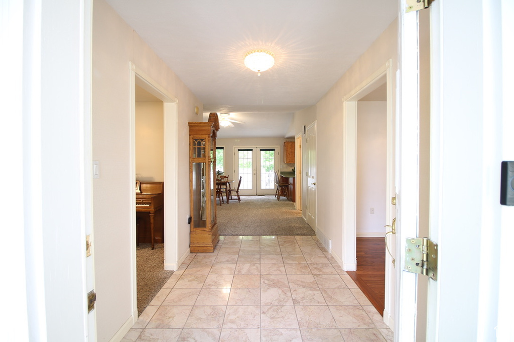 Hallway featuring light marble finish floors, baseboards, french doors, and light carpet