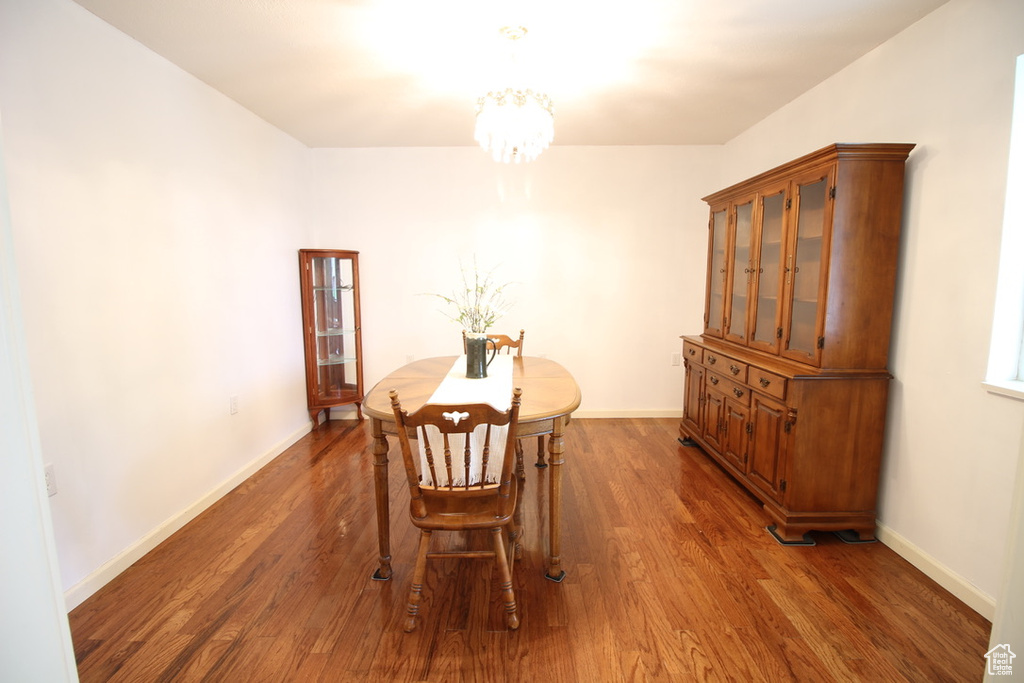 Dining room with a chandelier, dark wood-style flooring, and baseboards