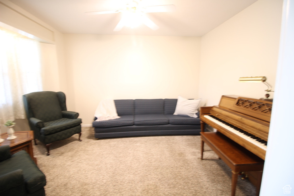 Carpeted living area featuring a ceiling fan