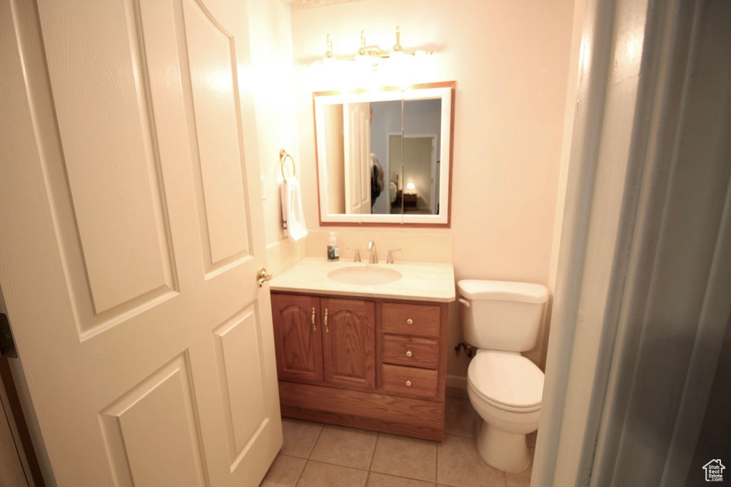 Half bathroom with tile patterned flooring, toilet, and vanity