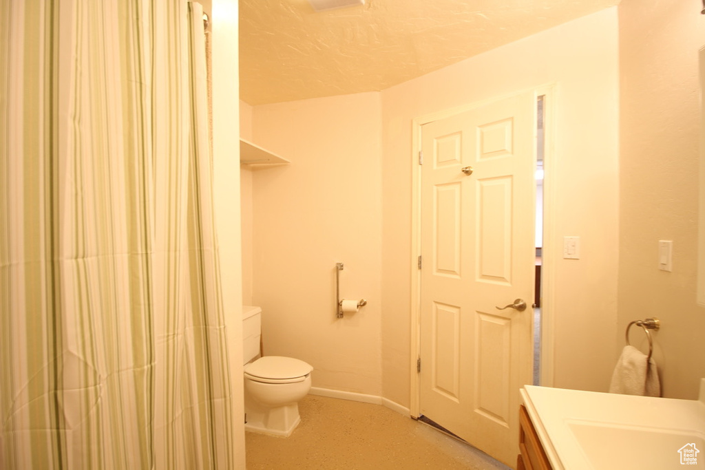 Full bath with toilet, vanity, baseboards, and curtained shower