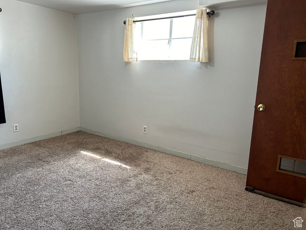 Carpeted spare room featuring baseboards