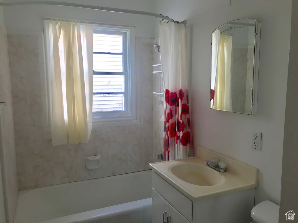 Full bathroom with toilet, vanity, and shower / tub combo