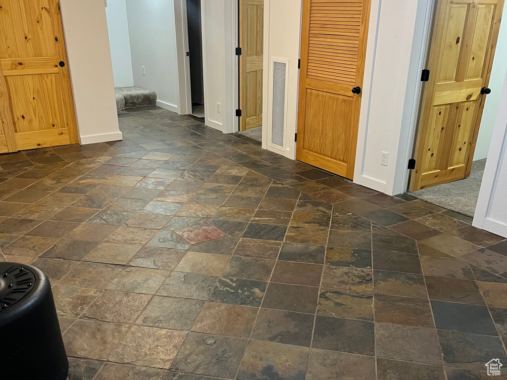Unfurnished bedroom featuring stone tile floors and baseboards