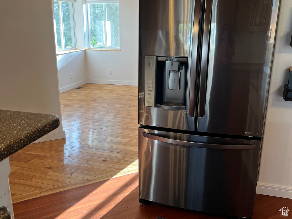 Kitchen with stainless steel fridge with ice dispenser, wood finished floors, and baseboards