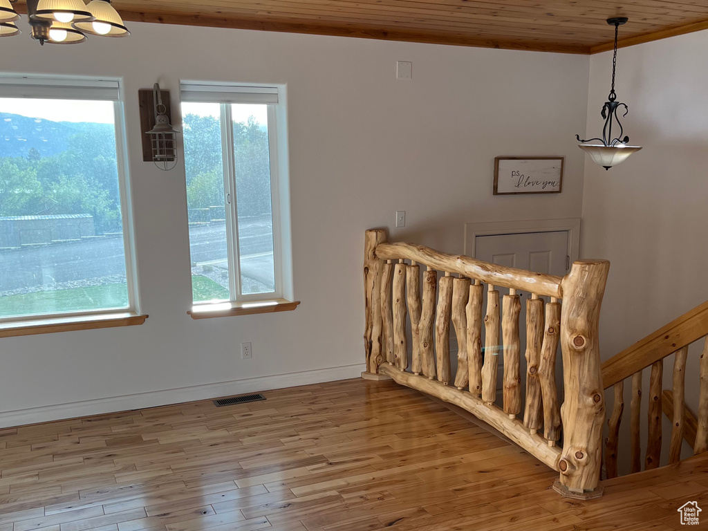 Staircase featuring a chandelier, wood finished floors, wooden ceiling, and baseboards