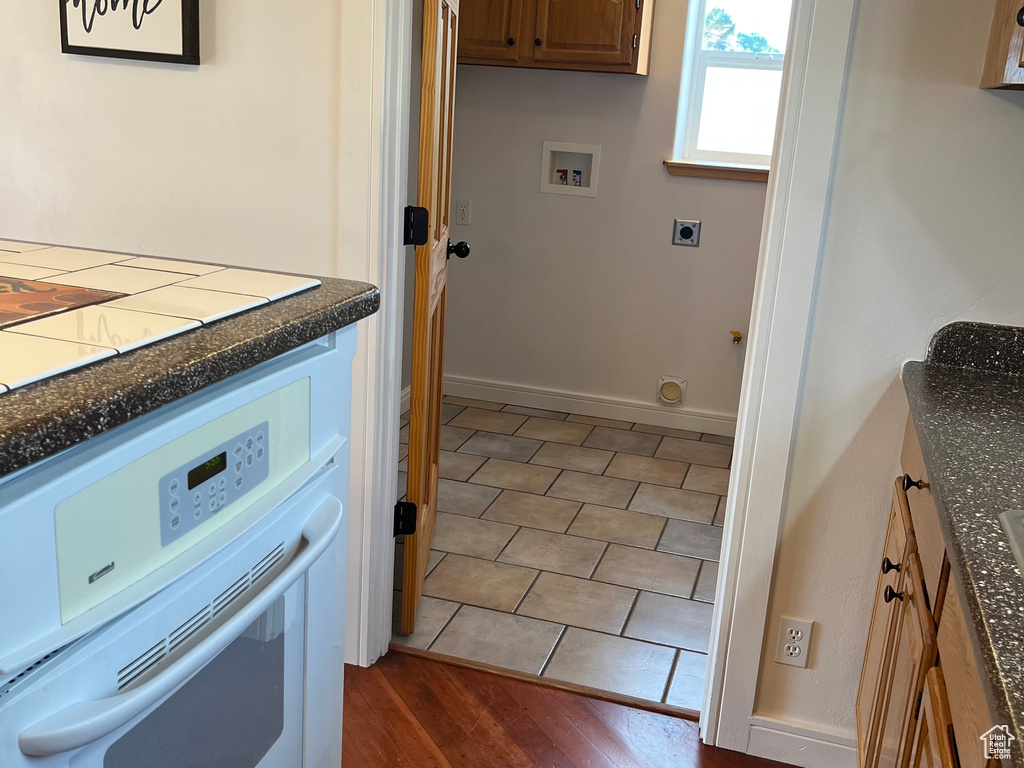 Clothes washing area featuring hookup for an electric dryer, washer hookup, and cabinet space