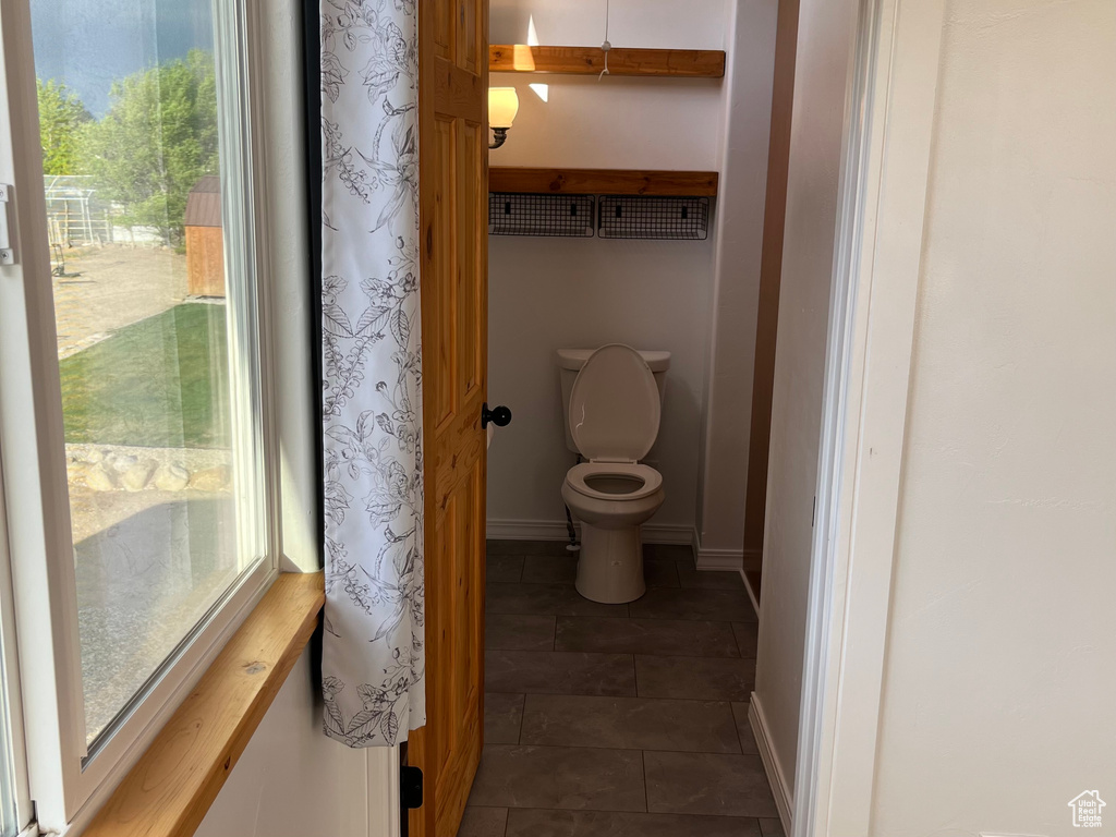 Bathroom with plenty of natural light, tile patterned flooring, toilet, and baseboards