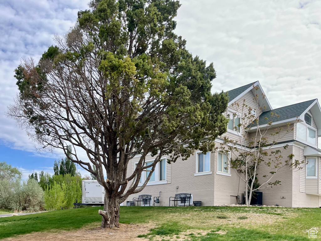 View of home\'s exterior with brick siding and a lawn
