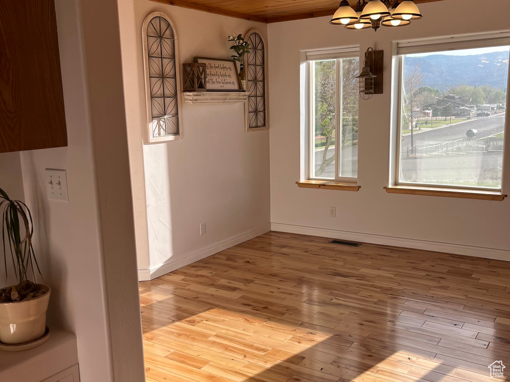 Unfurnished dining area with hardwood / wood-style flooring, a chandelier, and baseboards