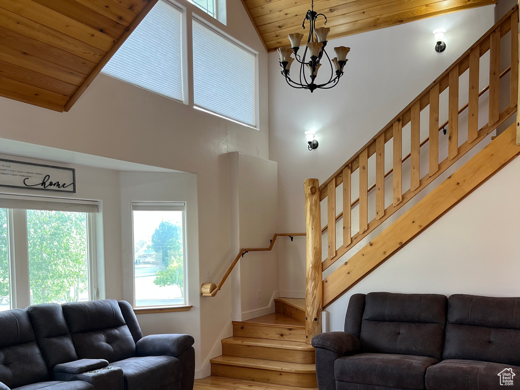 Living room with stairs, wooden ceiling, wood finished floors, healthy amount of natural light, and high vaulted ceiling