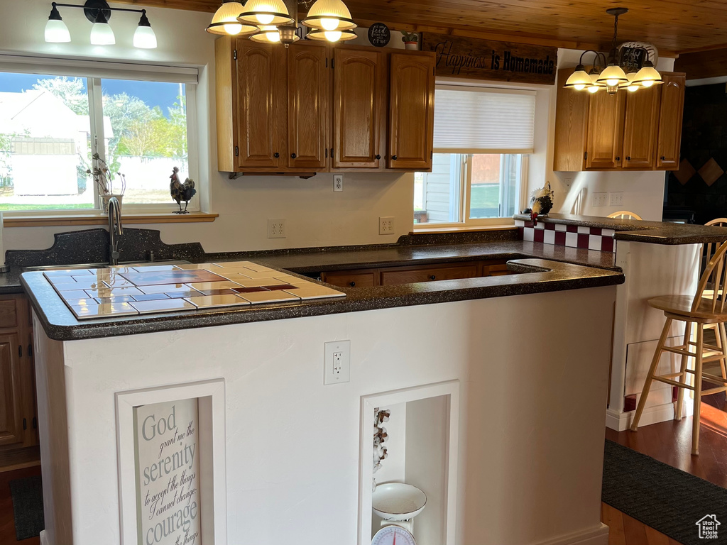 Kitchen featuring a peninsula, a chandelier, and dark countertops