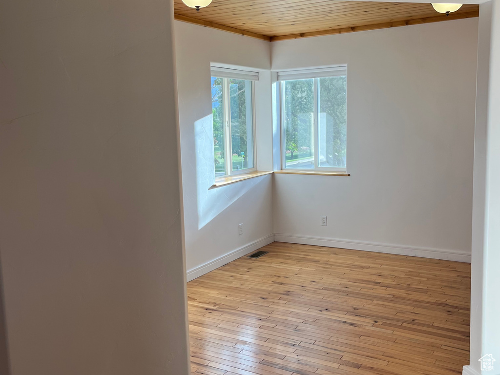 Spare room with wooden ceiling, light wood-style floors, and baseboards