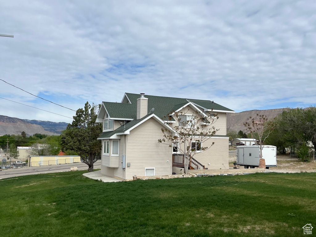 Rear view of house with a mountain view, a chimney, and a yard