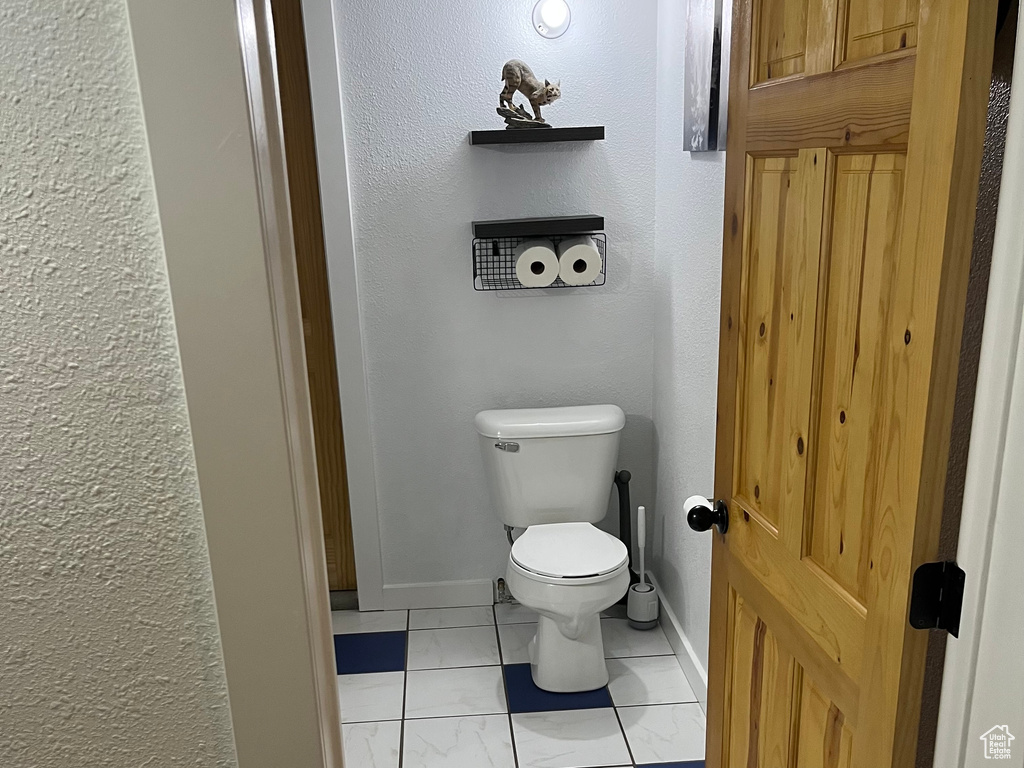 Bathroom featuring marble finish floors, toilet, and baseboards