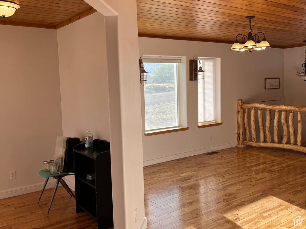 Living room with wood ceiling, wood finished floors, baseboards, a chandelier, and ornamental molding