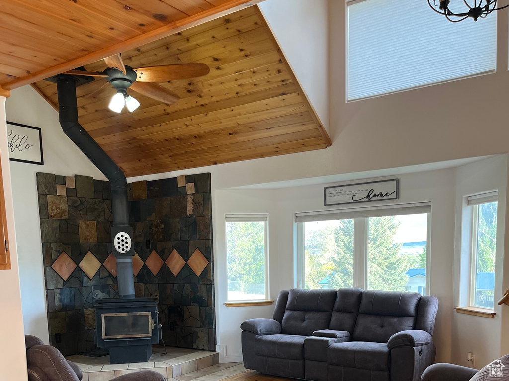 Living area featuring a wood stove, wooden ceiling, a ceiling fan, and high vaulted ceiling