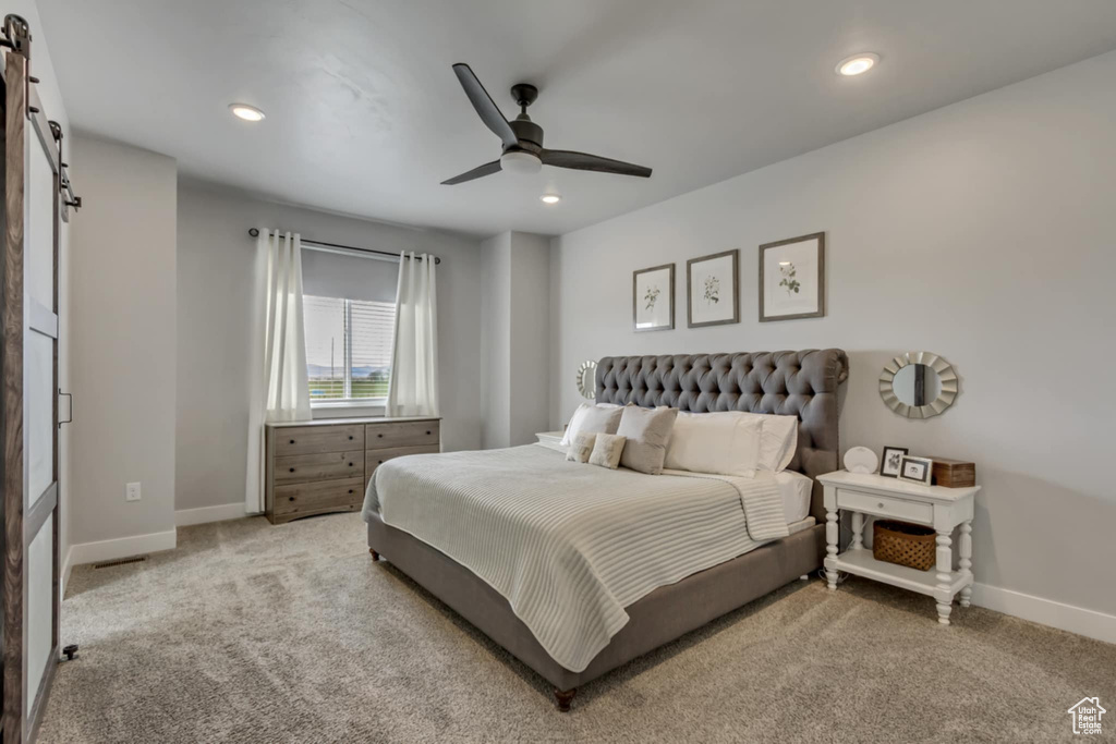 Bedroom featuring a barn door, baseboards, light carpet, recessed lighting, and a ceiling fan