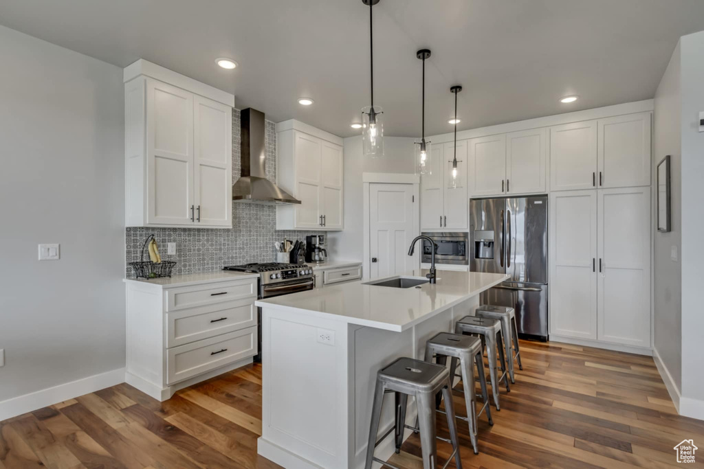 Kitchen with wall chimney exhaust hood, stainless steel fridge, a sink, recessed lighting, and dark wood-style flooring