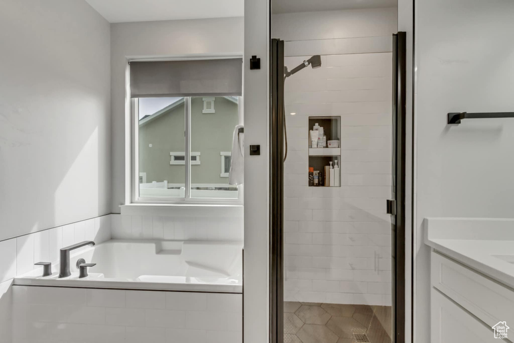 Bathroom featuring a shower stall, a garden tub, and vanity
