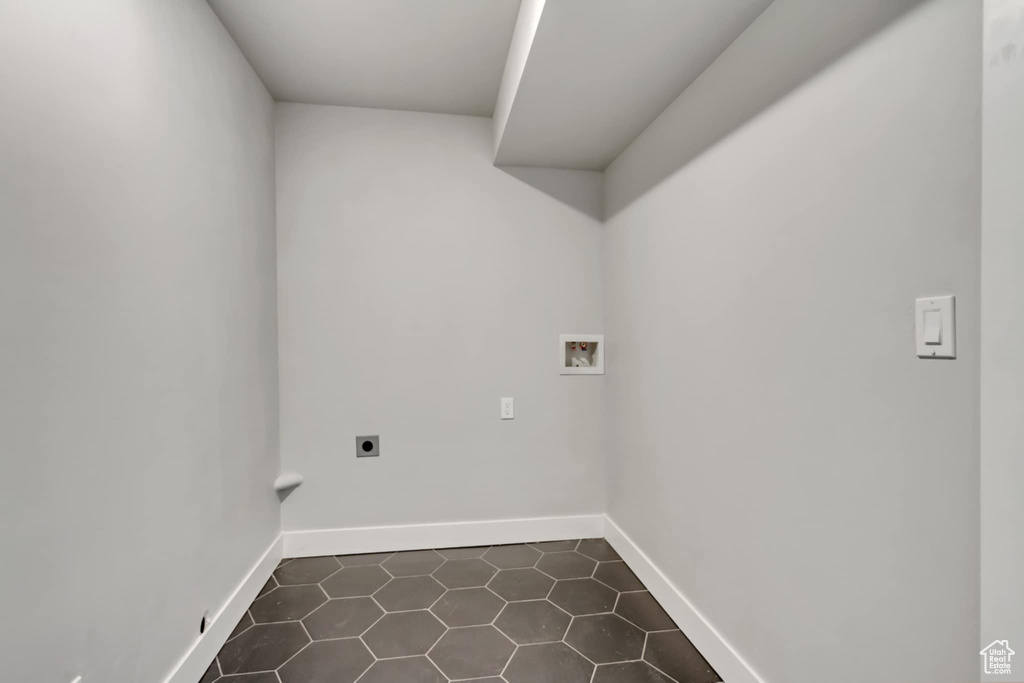 Laundry room featuring hookup for an electric dryer, washer hookup, dark tile patterned flooring, and baseboards