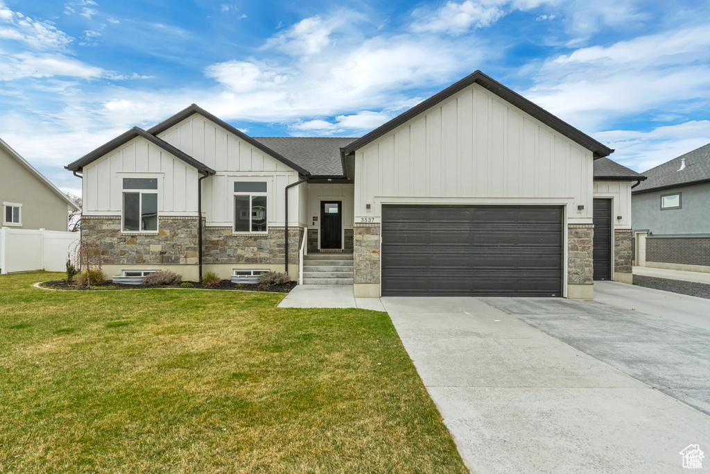 View of front of house with board and batten siding, concrete driveway, stone siding, a garage, and a shingled roof