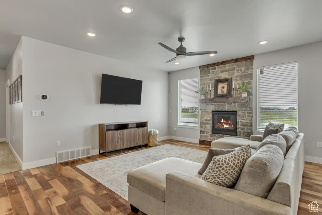 Living room with a fireplace, ceiling fan, wood finished floors, baseboards, and recessed lighting