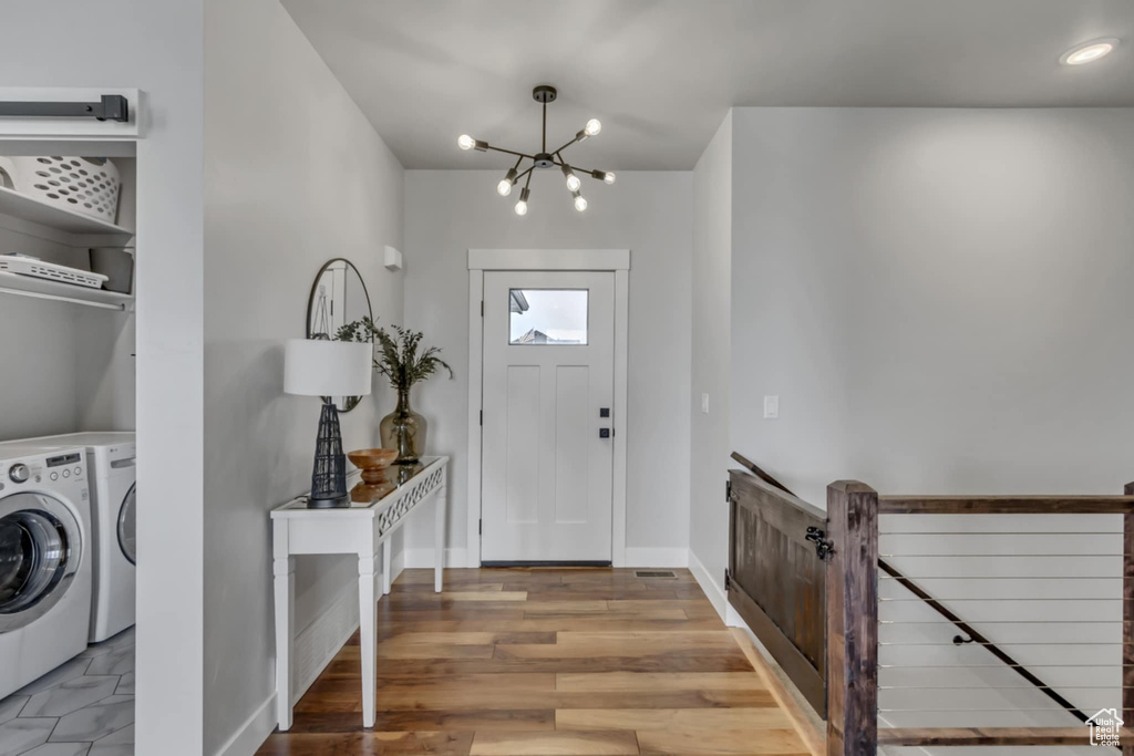 Entryway featuring washing machine and clothes dryer, a chandelier, baseboards, and wood finished floors