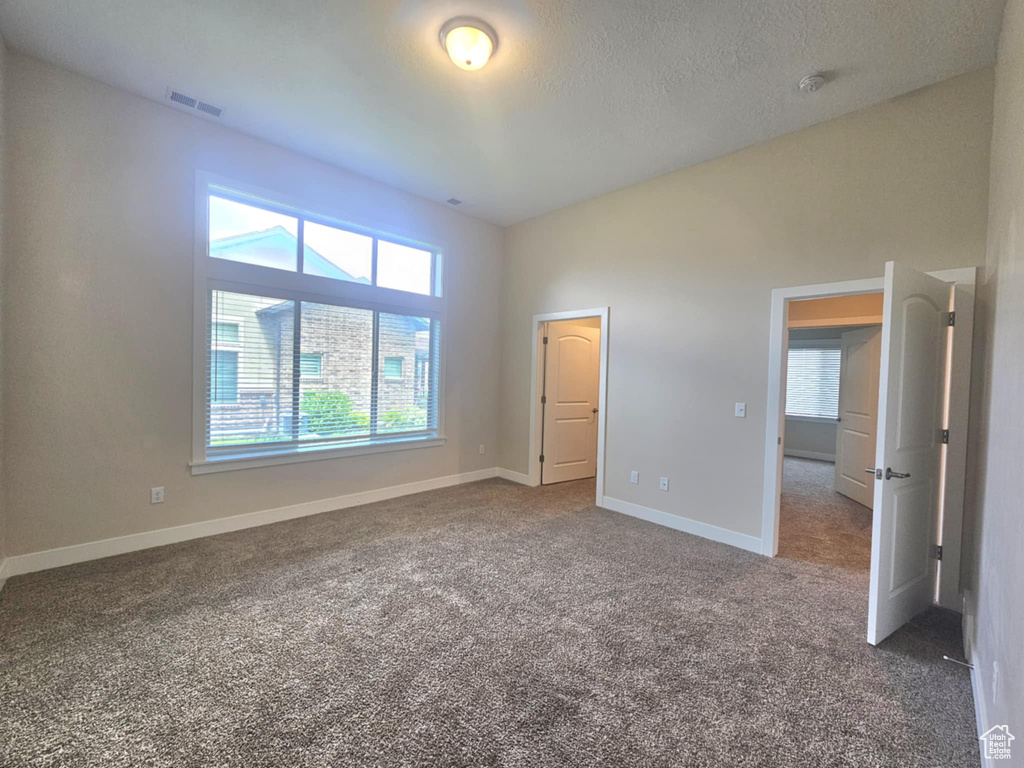 Unfurnished bedroom with carpet floors, baseboards, and a textured ceiling