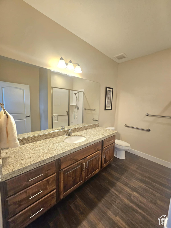 Bathroom featuring wood finished floors, a stall shower, vanity, baseboards, and toilet