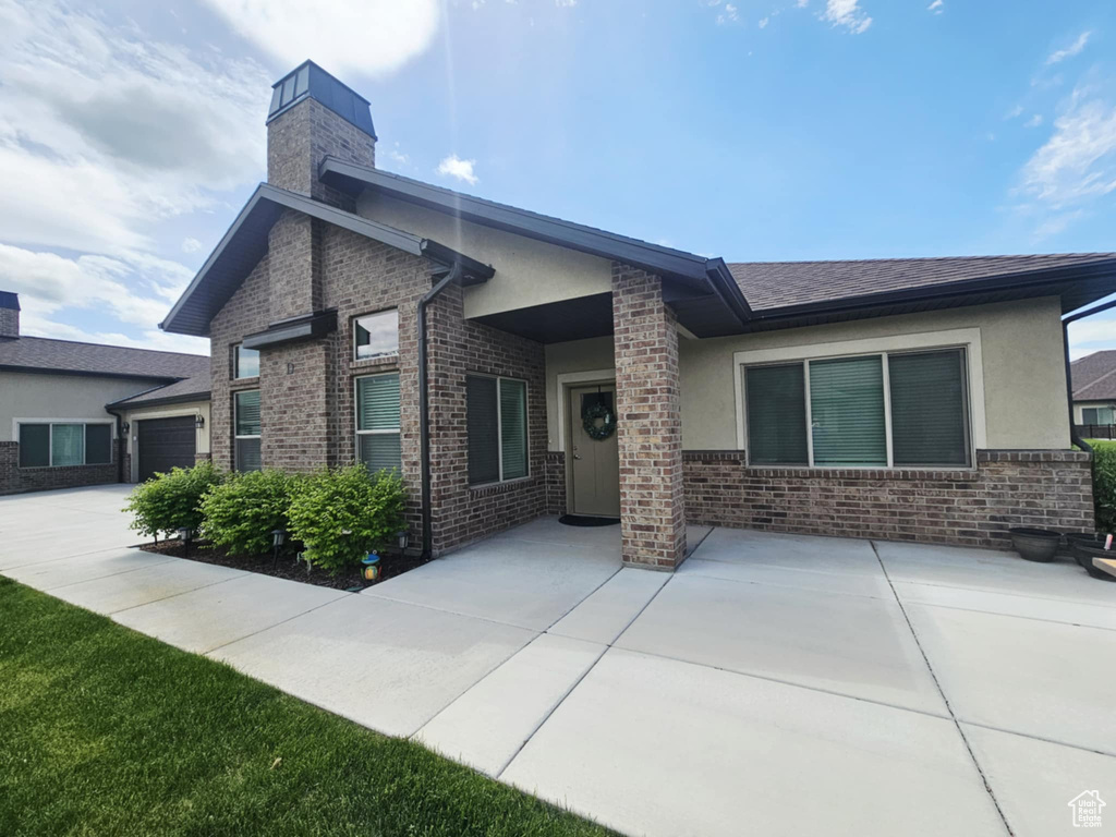 Back of house with a chimney, stucco siding, and brick siding