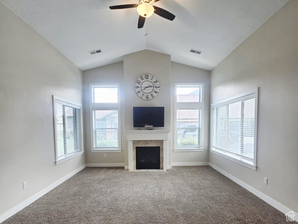 Unfurnished living room with a fireplace, a ceiling fan, lofted ceiling, healthy amount of natural light, and baseboards