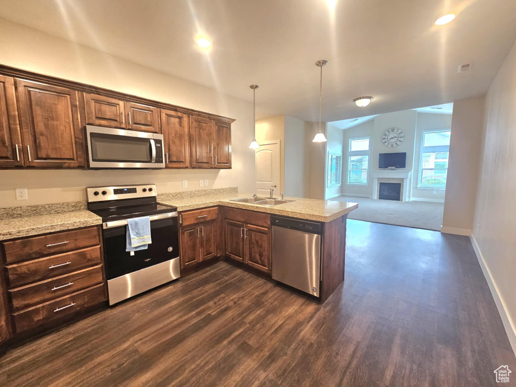 Kitchen featuring appliances with stainless steel finishes, a sink, dark wood-type flooring, and open floor plan