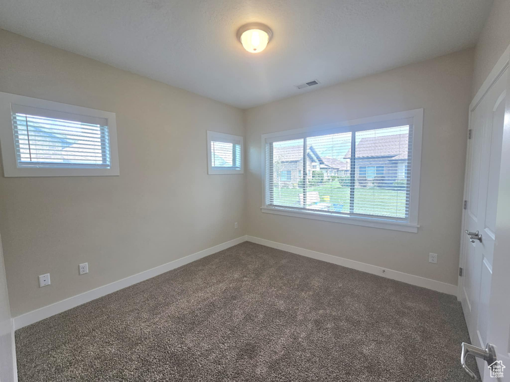 Unfurnished room with dark carpet and baseboards