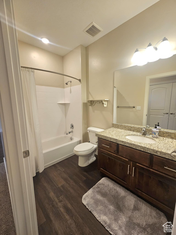 Bathroom with wood finished floors, vanity, toilet, and shower / bath combination with curtain
