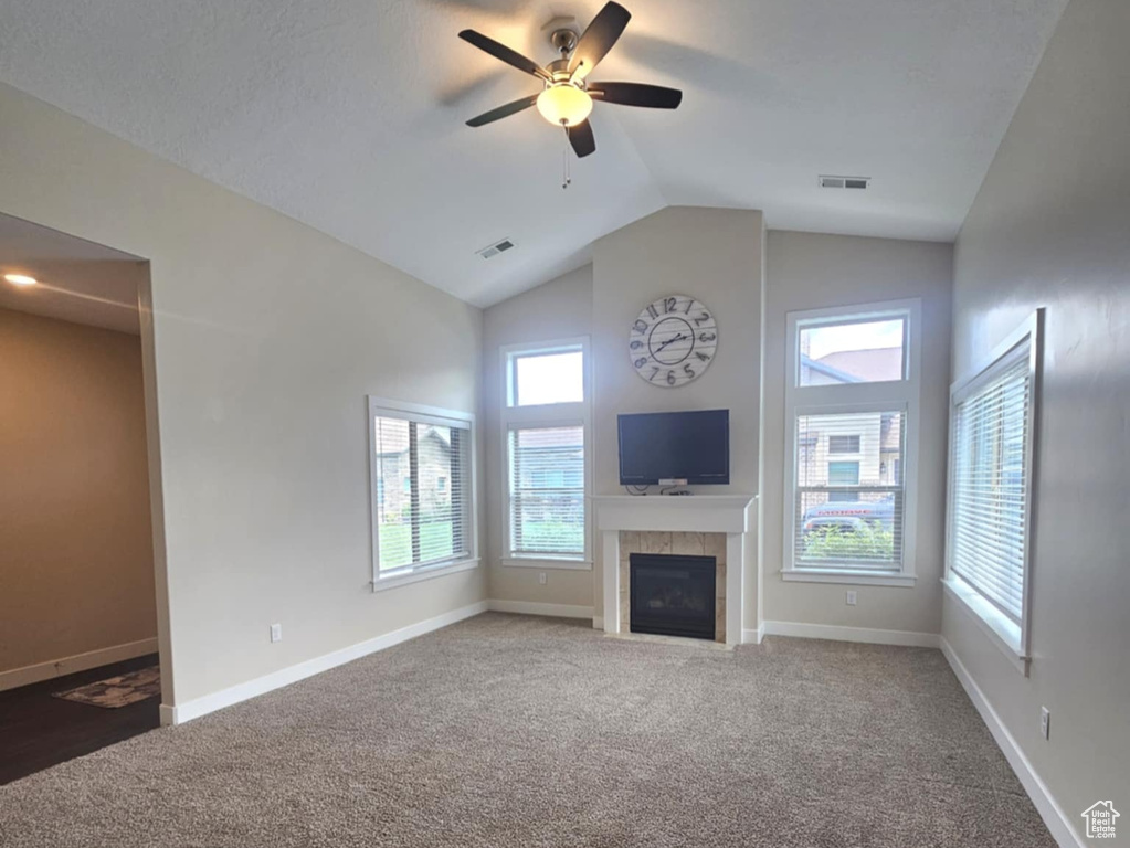 Unfurnished living room featuring ceiling fan, a fireplace, plenty of natural light, lofted ceiling, and baseboards