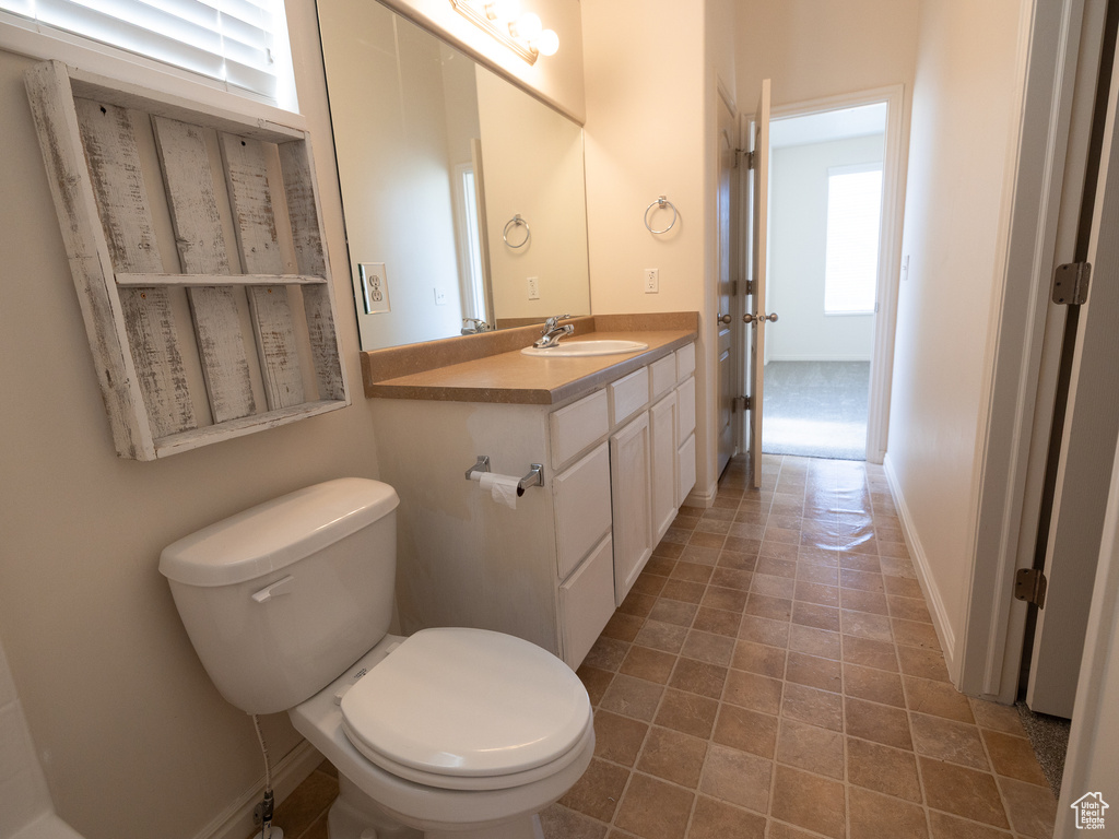Half bath featuring toilet, vanity, and baseboards