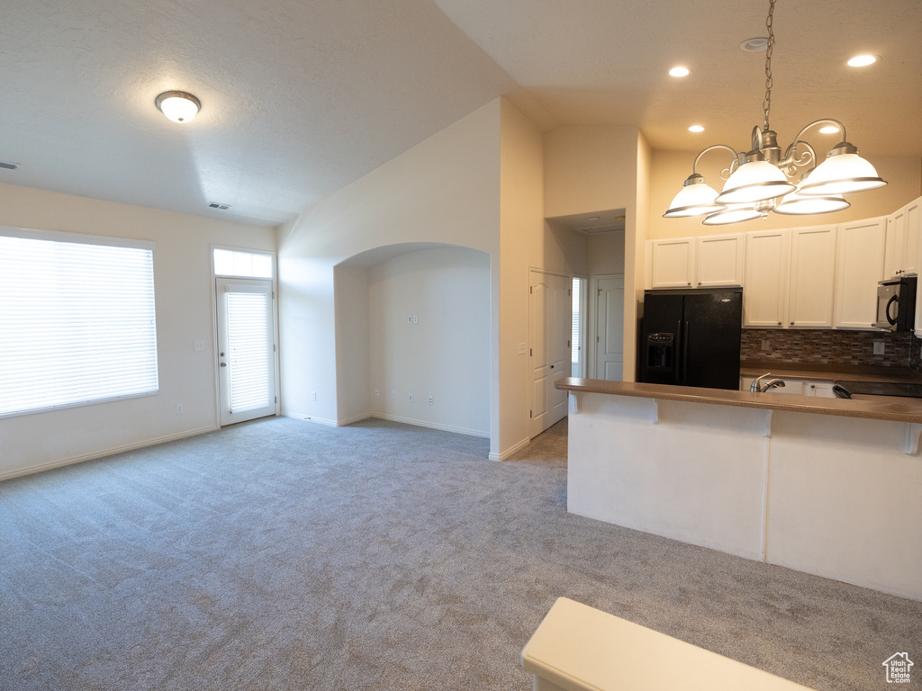 Kitchen featuring black appliances, a chandelier, light colored carpet, dark countertops, and recessed lighting