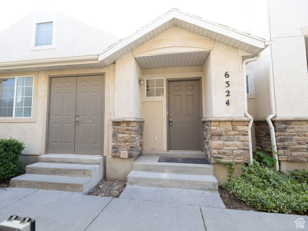 Doorway to property featuring stone siding and stucco siding