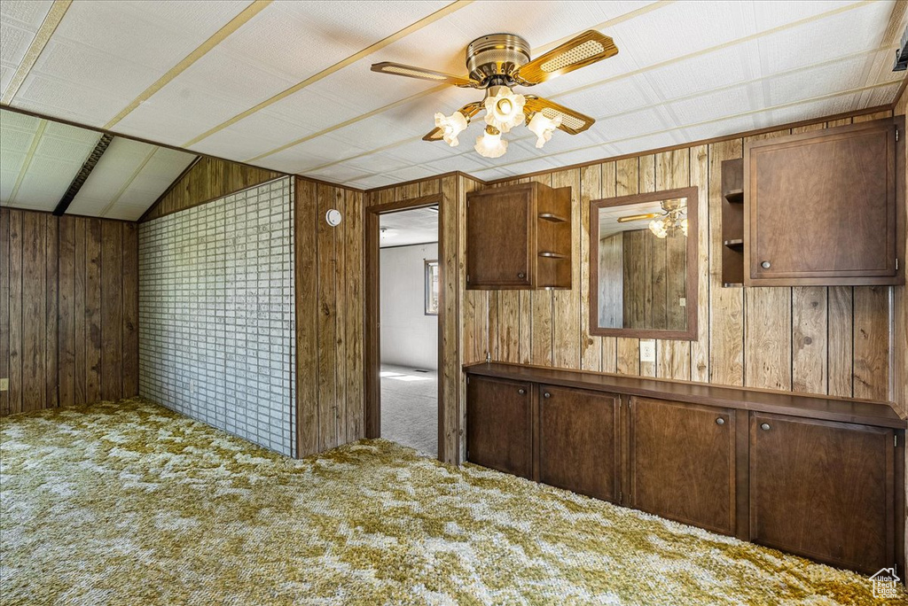 Kitchen with ceiling fan, carpet floors, wood walls, and lofted ceiling