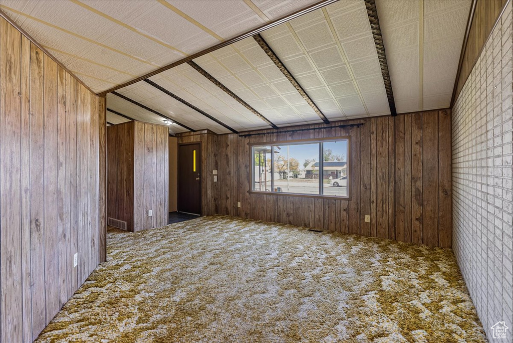 Unfurnished room featuring carpet flooring and wooden walls