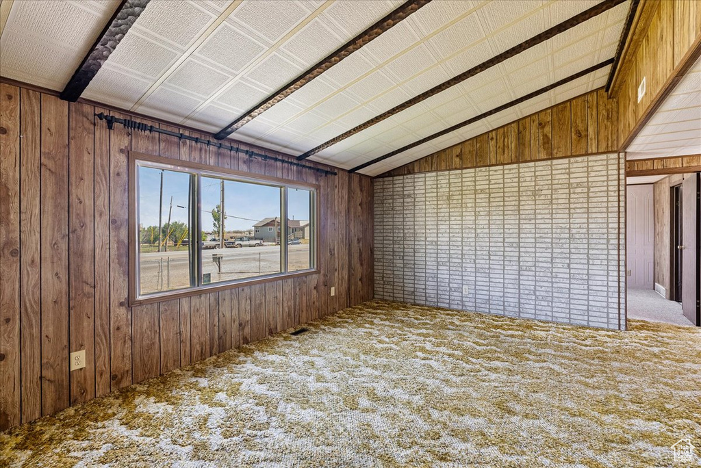 Empty room featuring wooden walls, carpet floors, and lofted ceiling