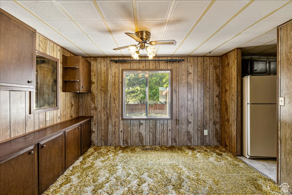 Kitchen featuring freestanding refrigerator, wooden walls, carpet flooring, ceiling fan, and open shelves