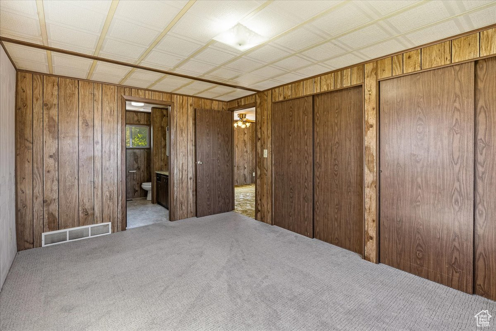 Bedroom featuring wood walls, carpet, two closets, and connected bathroom