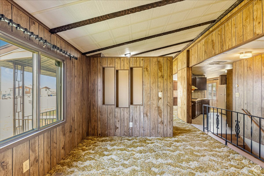 Unfurnished room featuring wood walls and carpet