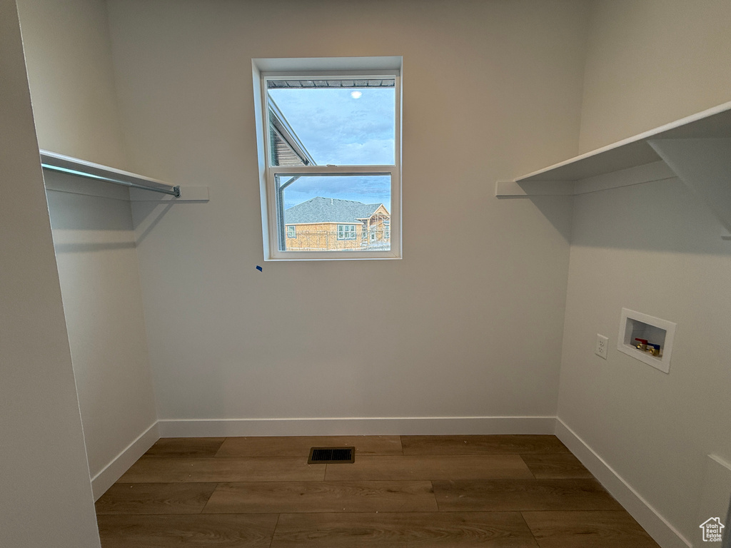 Clothes washing area with hookup for a washing machine, wood finished floors, and baseboards