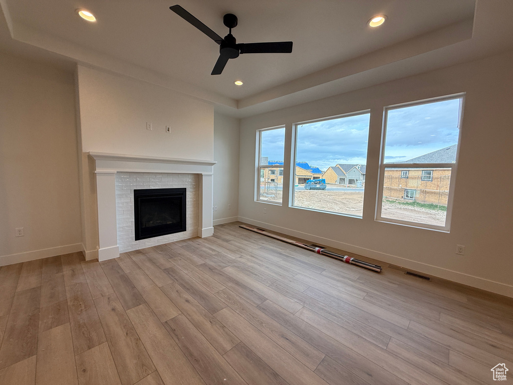 Unfurnished living room with a tray ceiling, ceiling fan, light wood-style flooring, baseboards, and recessed lighting