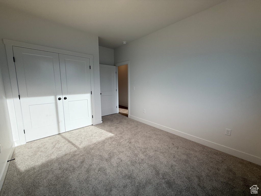 Unfurnished bedroom featuring carpet floors, baseboards, and a closet