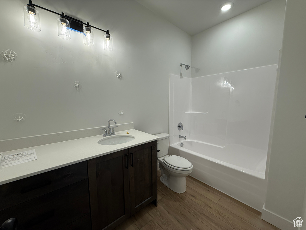 Full bath with wood finished floors, toilet, vanity, and shower / bath combination