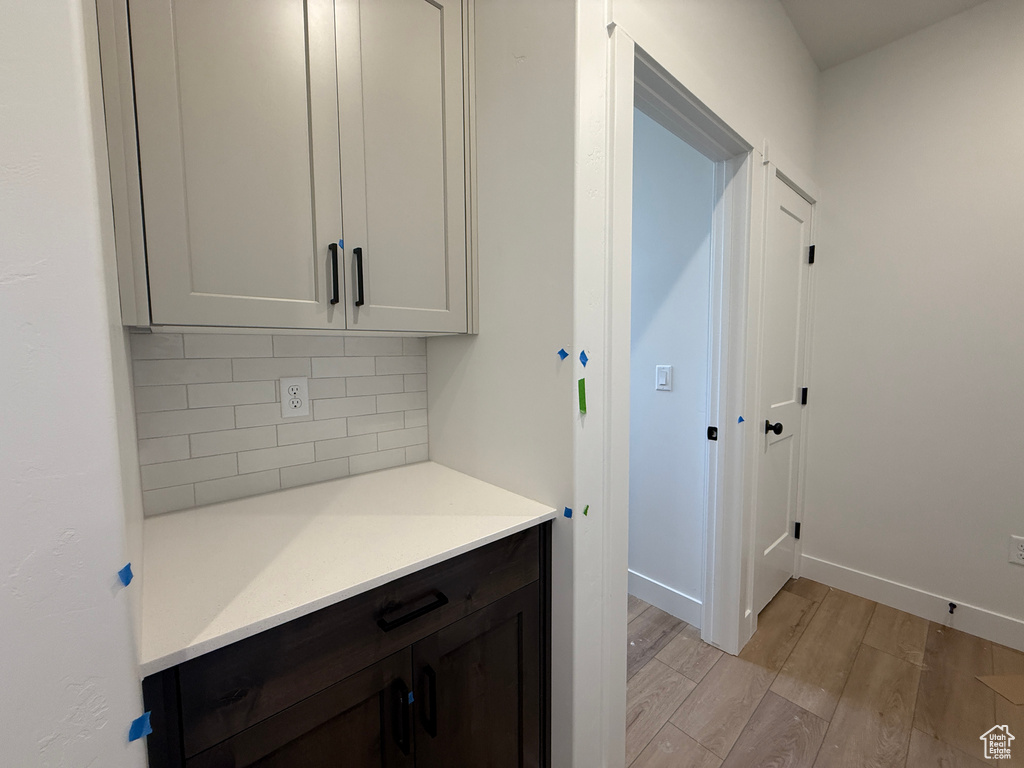 Kitchen featuring light wood-style floors, backsplash, light countertops, and baseboards